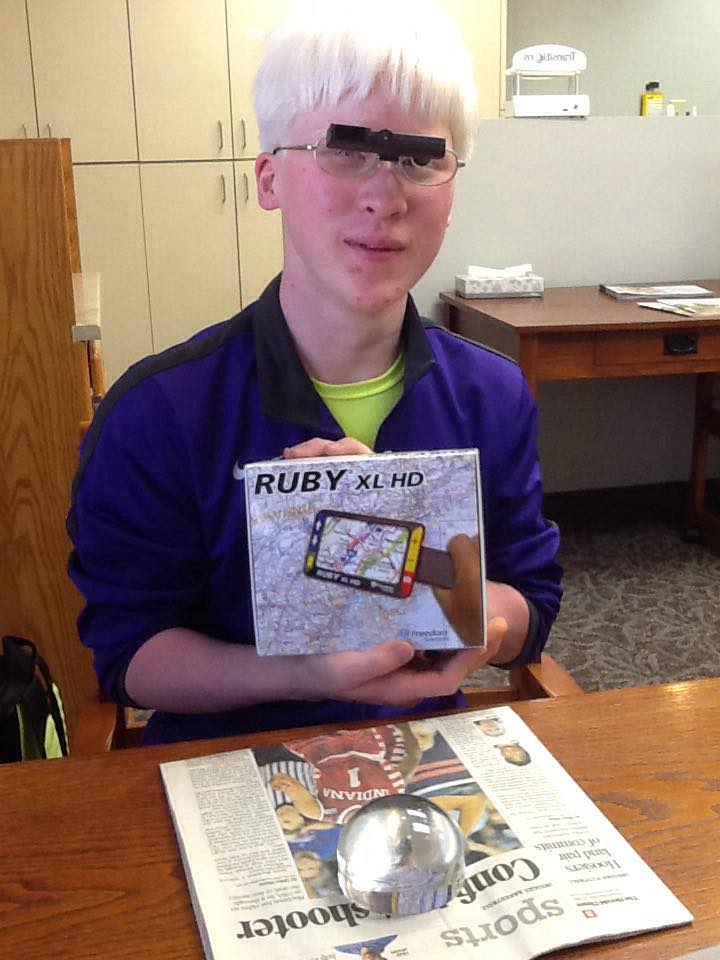 Jacob wearing his bioptic glasses and holding his Ruby video magnifier