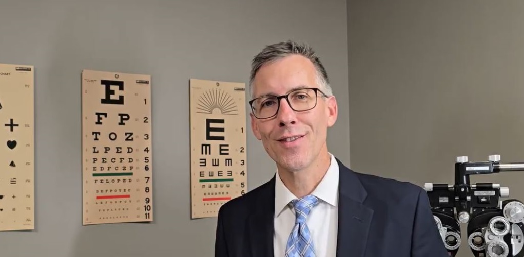 Low vision doctor, Dr. Long, in front of eye chart discussing what is a low vision doctor